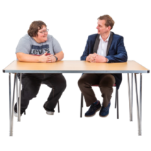 An employer and employee sitting next to each other at a desk and having a conversation.